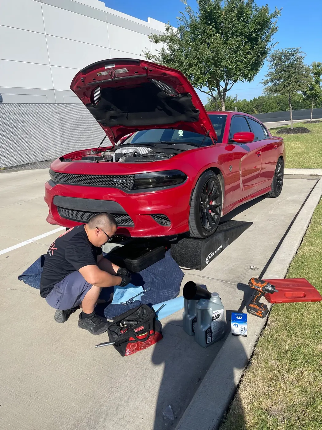 SPARK technician working on a red Dodge Charger at the customer's location