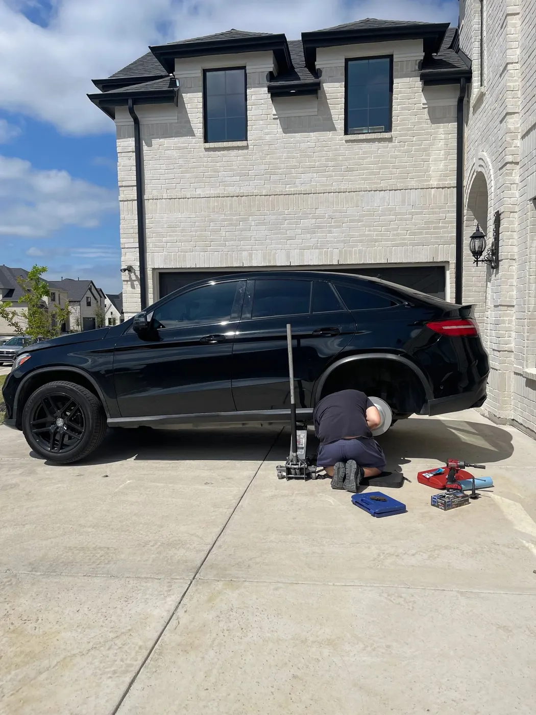 SPARK mobile mechanic servicing a black Mercedes SUV in a customer's driveway
